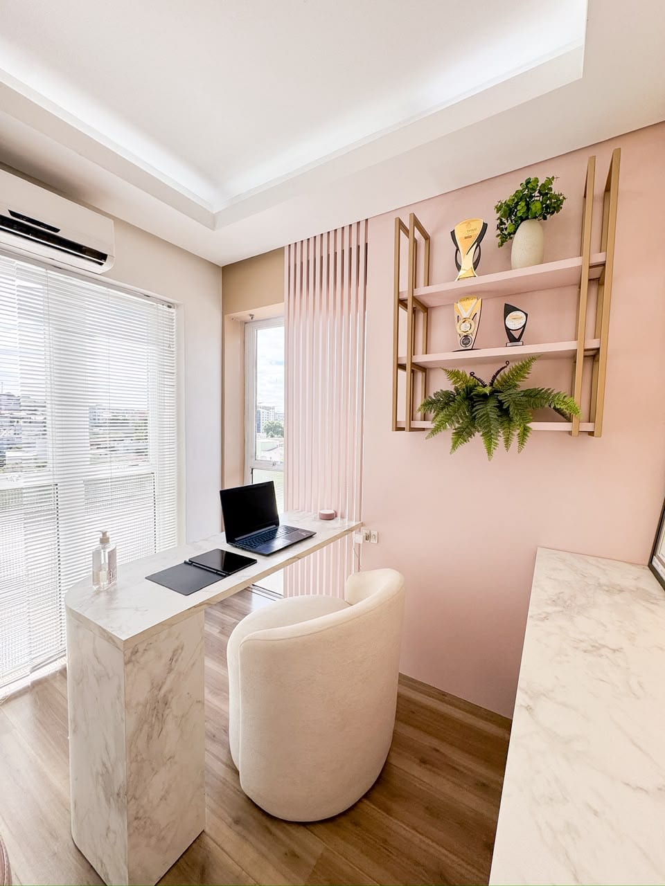 Sala da BN Clinic com parede blush, prateleiras douradas e bancada de mármore